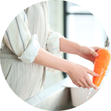 キッチンに立っている人がにんじんを水で洗っている写真